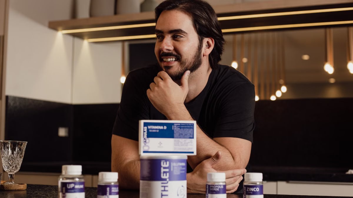 A man enjoying wellbeing surrounded by supplement bottles in a modern kitchen.